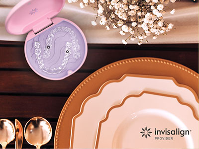 The image displays a collection of dinnerware items, including plates and serving dishes, arranged on a table with various decorative elements such as flowers, candles, and a box that appears to be for dental care products.
